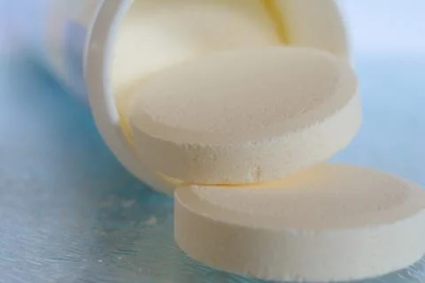 Soluble tablets falling out the plastic tube on glass table top - closeup. Sh Stock Photos