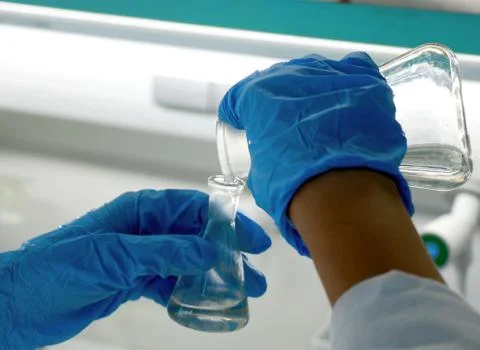 Solution in a glass flask with scientist hands Stock Photos
