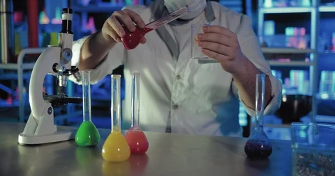 Solution is poured from a flask into a glass beaker in a chemical laboratory Video stock 104110332