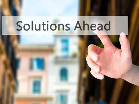 Solutions Ahead - Hand pressing a button on blurred background c Stock Photos