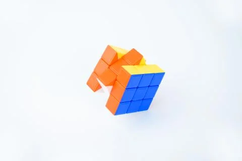 A solved rubik's cube on a white background displaying bright blue orange and Stock Photos