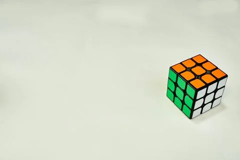 Solved rubik's cube in white, green and orange on white background with copy Stock Photos