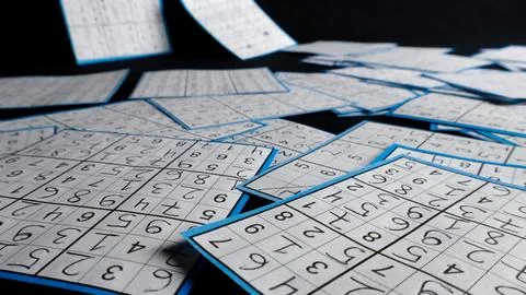Solved sudoku puzzles scattered on dark background Stock Photos
