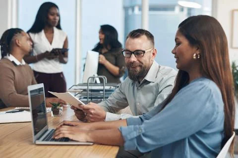 Solving business problems with a smile. two young businesspeople sitting Foto stock