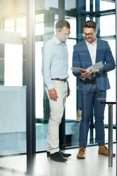 Solving problems as a team. two businessmen talking over some paperwork in an Stock Photos