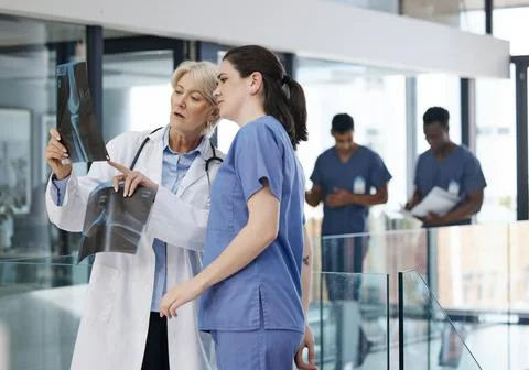Solving problems together. two female doctors examining an x-ray at a modern 写真素材