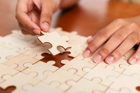 Solving the puzzle hands placing last piece indoor setting close-up focus o.. 스톡 사진