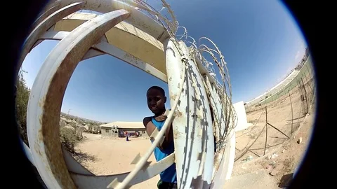 Somali kid climbs behind barbed wire Stock Footage 86329021
