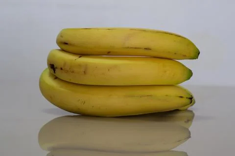 Some bananas on a table and their reflection Stock Photos