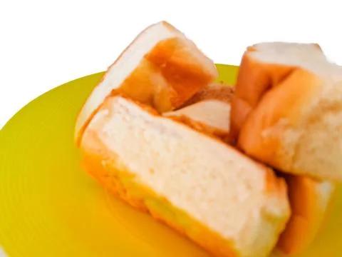 Some bread on a yellow plastic plate, isolated on a white background Stock Photos