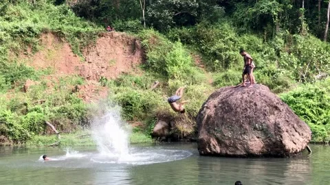 Some children bathed in the river and jumped on the big rocks Stock Footage 229178486