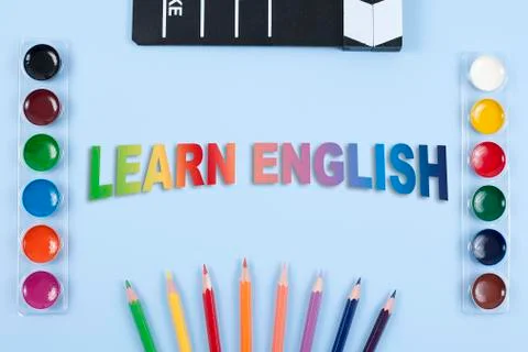 Some colored pencils of different colors, watercolor and film clapper on blue Stock Photos