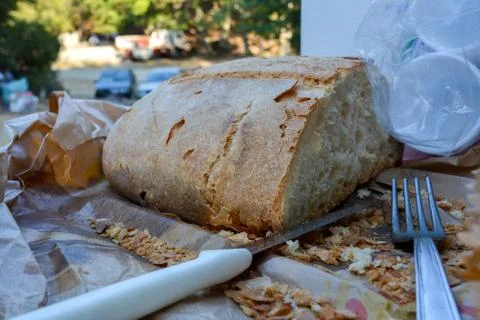 Some cut bread, a steel fork and some plastic cups Stock Photos