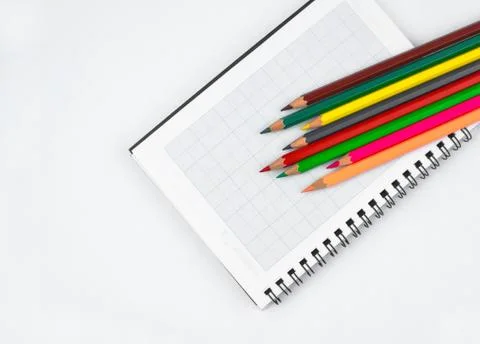 Some different colored pencil crayons scattered on top of an open white paper Stock Photos
