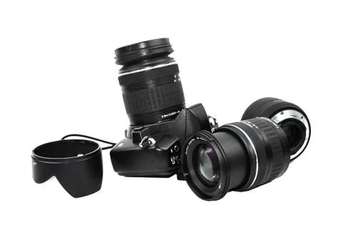 Some different part of a black digital camera scattered across a white backgr Stock Photos