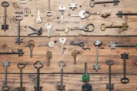 Some door keys aligned on old wooden surface, safety and security concept Stock Photos