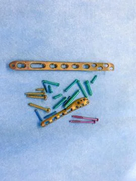 Some explanted titanium screws and titanium plates in different colors and si Stock Photos