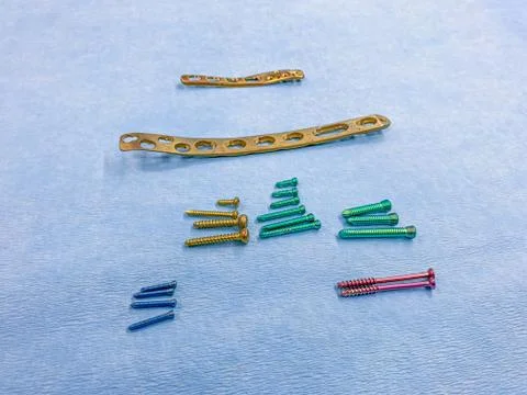 Some explanted titanium screws and titanium plates in different colors and si Stock Photos