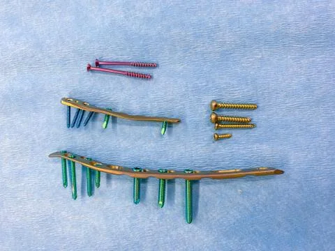 Some explanted titanium screws and titanium plates in different colors and si Stock Photos