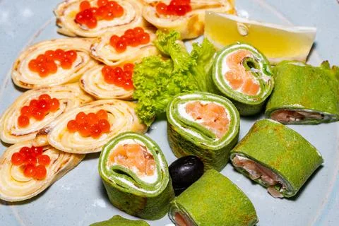 Some green sushi with red fish and pancakes with red caviar close-up Stock Photos