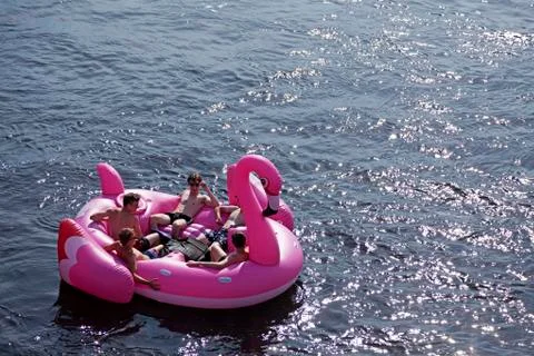 Some guys float around in a huge inflatable falamingo on the river Stock Photos