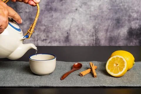 Some hands holding a teapot while pouring the hot water to prepare the tea,.. Stock Photos