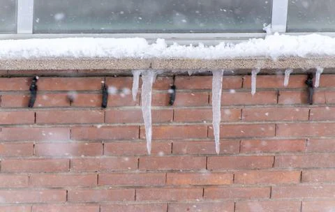 Some icicles under a window ledge in a snow stormy day. 스톡 사진