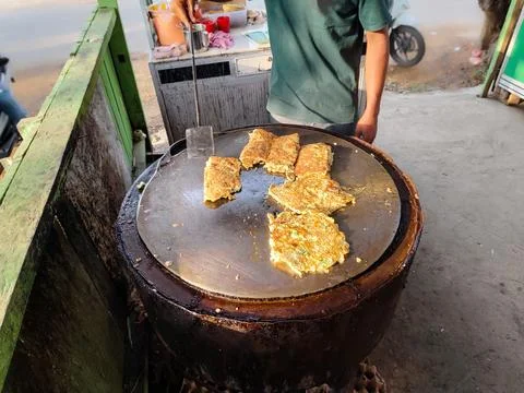 Some martabak being fried in a flat round pan Stock Photos