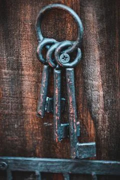 Some old rusty keys hanging on a wooden key chain Stock Photos