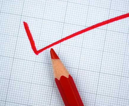 Some one writing with a red colored wood pencil crayon over a graph paper Stock Photos
