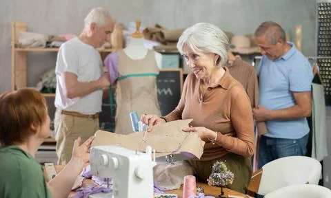 Some people discuss pattern, while others sew using sewing machine, work with 스톡 사진