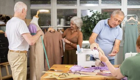 Some people discuss pattern, while others sew using sewing machine, work with Stock Photos