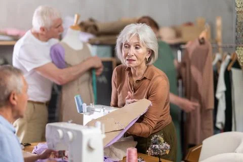Some people discuss pattern, while others sew using sewing machine, work with Stock Photos