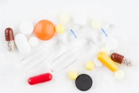 Some pills and two vials on the medical table Stock Photos