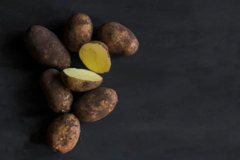 Some potatoes on a dark table Stock Photos