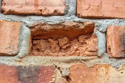 Some red bricks in the wall have crumbled due to weathering. Stock Photos