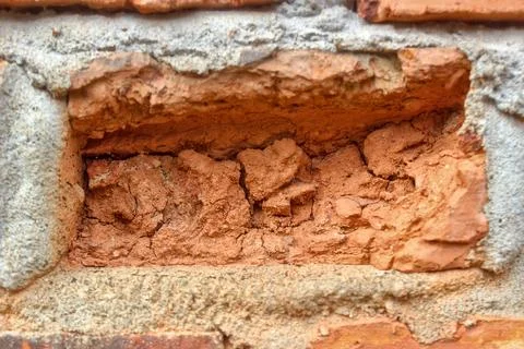 Some red bricks in the wall have crumbled due to weathering. Stock Photos