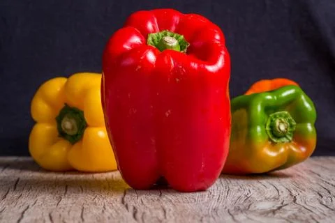Some red, green and yellow bell peppers over a wooden surface. Stock Photos