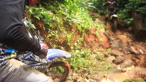 Some riders having hard time to go down some rocks on a dirt bike Stock Footage 89731745