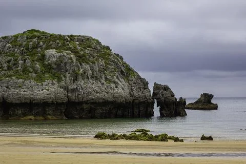 Some rocks on a beach witha cloudy sky Stock Photos