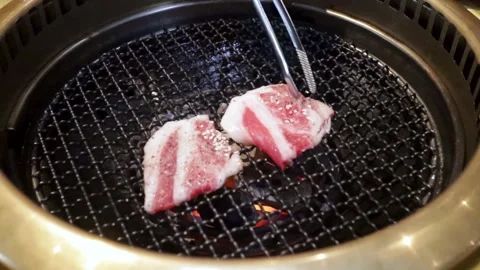 Some slice of meat being grilled in a modern round or circle barbeque grill.. Stock Footage 257609719