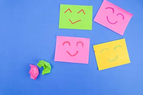 Some sticky notes with 4 expressions drawn with red and green markers on a bl Stock Photos