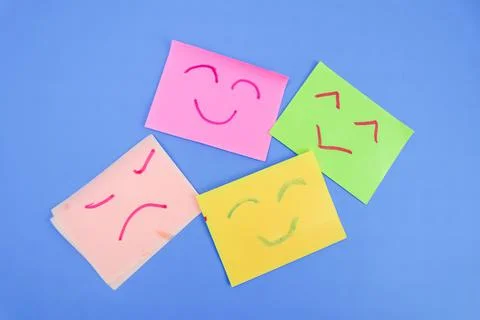 Some sticky notes with 4 expressions drawn with red and green markers on a bl Stock Photos