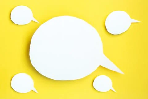 Some white paper speech bubbles with clipping path on bright yellow backgroun Stock Photos