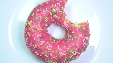 Somebody bit a glazed sprinkles donut. Yummy slowly spinning on a rotating table Stock Footage 89729033