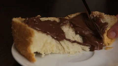 Somebody smears freshly cooked bread with chocolate paste Stock Footage 69911304
