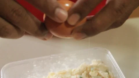 Someone adds eggs to the flour mixture. Someone makes a dish made from flour Stock Footage 334647498