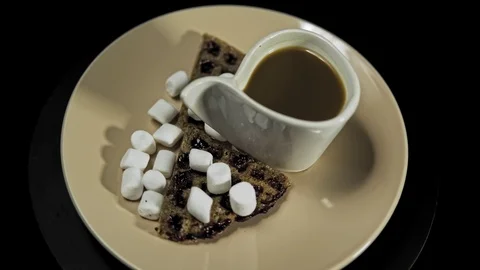 Someone adds marshmallows to dark waffles on a colored plate. Stock Footage 100188313