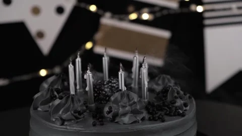 Someone blowing out burning silver candles on stylish black birthday cake. Stock Footage 318940185