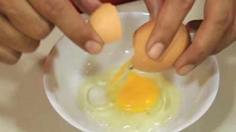 Someone breaks an egg in a bowl. Beat the eggs in a white bowl Stock Footage 334268139